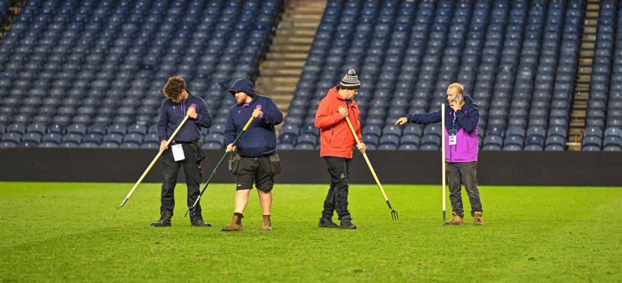 Scottish Rugby employees on field checking grass with rakes